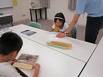 本に透明なカバーをはっているところです。（なかがわ図書館　「子ども図書館大使」）