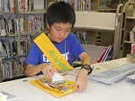 １さつずつていねいに、貸出や返却をします。（もりやま図書館　「子ども図書館大使」）