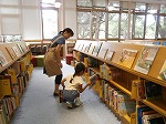 本をたなに返しています。教えてもらいながらばっちり！（みずほ図書館　「子ども図書館大使」）