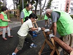 丸太切りに挑戦！のこぎりは体全体を使って引きます。（あつた図書館　熱田白鳥で木工体験！）