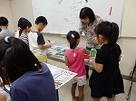 折りたたんだ和紙に色をつけます。（くすのき図書館　夏休み工作教室「おりぞめでつくろう！自分だけのうちわ」）