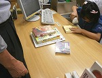 1冊ずつ、ていねいにバーコードをよんでいきます。（みずほ図書館　「なごやっ子読書ノートでカウンター体験」）