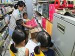 書庫で新聞の縮刷版を見ています。（てんぱく図書館　「なごやっ子読書ノートでカウンター体験」）