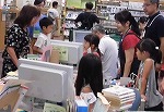 お客さんが来たら、えがおであいさつ。（なんよう図書館　「なごやっ子読書ノートでカウンター体験」）