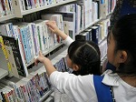 返却された本を棚に戻す様子。（とみだ図書館　「大型連休に図書館の仕事を体験してみよう）をおこないました）